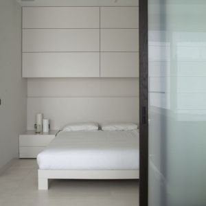 Dzięki drzwiom przesuwnym skomponowano ruchomą ścianę, która oddziela minimalistyczną, surową sypialnię od części dziennej mieszkania. Fot. Studio O.
