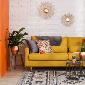 Sofa w kolorze ciepłej żółci dobrze wygląda na tle stonowanych kolorów. Fot. Salony Agata