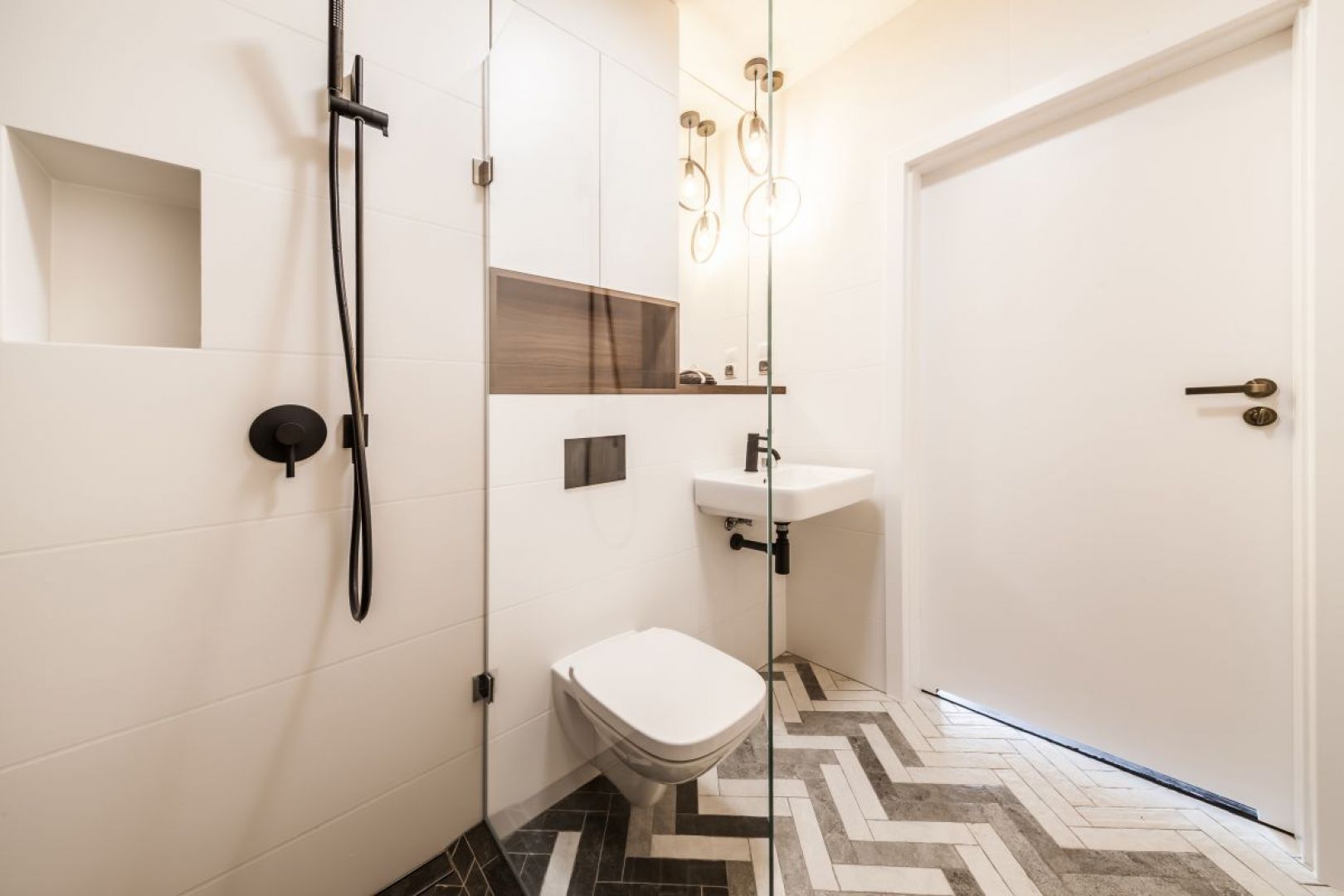 Motyw jodełki zastosowano także w projekcie łazienki, dzięki czemu współgra stylistycznie z pozostałą częścią mieszkania. Fot. Kodo