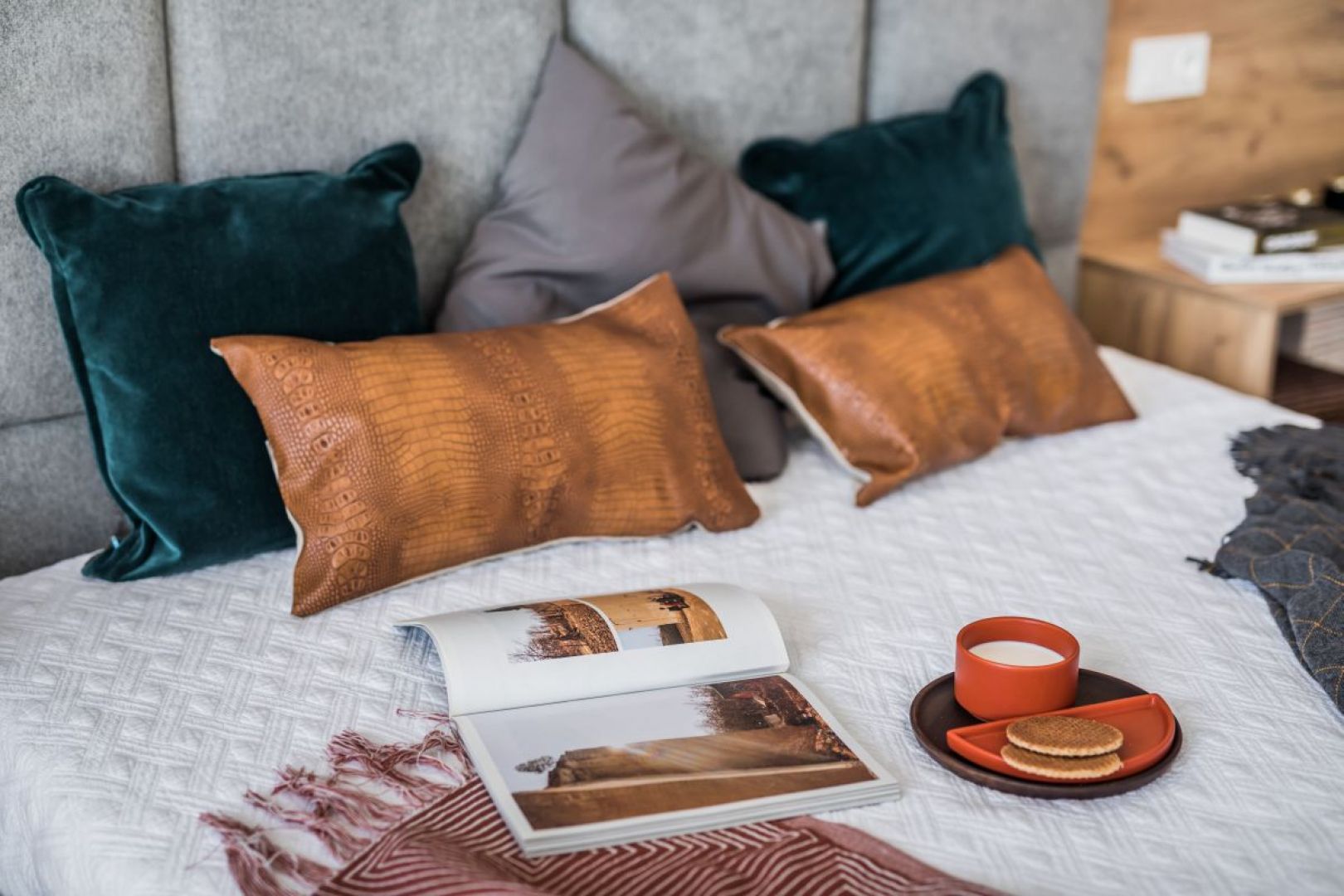 Minimalistyczny styl sypialni przełamują dodatki – wzorzysta narzuta, poduszki wykonane z aksamitnych, strukturalnych tkanin oraz tłoczonej skóry. Fot. Kodo