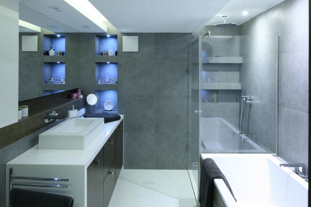 W projekcie łazienki uwagę zwraca praktyczne rozmieszczenie sprzętów oraz pomysłowe połączenie wanny z kabiną prysznicową. Ściana kabiny oparta o rant wanny to spora oszczędność miejsca.