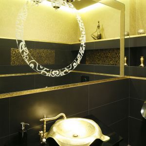 Na dużej tafli lustra wygrawerowano ramę – z ozdobnym motywem powtórzonym z dekoru płytek ceramicznych. Elegancki kinkiet z kryształków pięknie odbija się w lustrze. Proj. Magdalena Mirek-Roszkowska. Fot. Bartosz Jarosz
