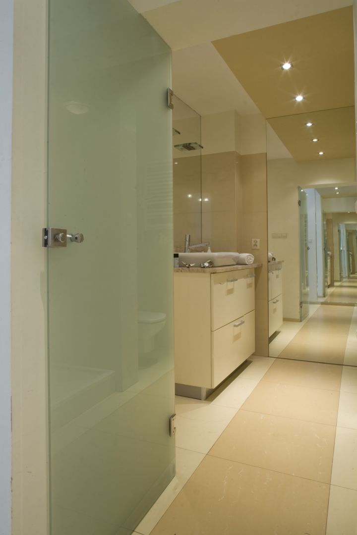 Optyczne wydłużenie łazienki zapewniają lustra i odpowiednio ułożone płytki gresowe. Drzwi ze szkła matowego sprawiają, że wnętrze wydaje się bardziej przestronne. Fot. Monika Filipiuk-Obałek