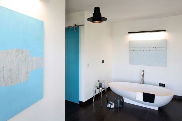 Toaleta przy sypialni ma artystyczny klimat loft.  Zlokalizowana jest w apartamencie pokazowym na warszawskim Mokotowie. Płynnie łączy się z sypialnią - w niej ustawiono bowiem komfortową wannę!