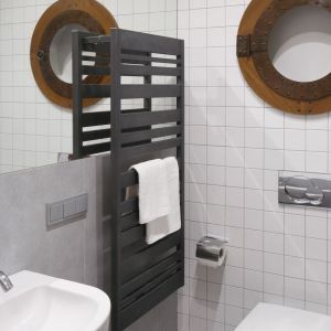 Duża tafla lustra na ścianie za umywalką pozwala optycznie powiększyć jasną łazienkę. Ciemnoszary grzejnik jest nie tylko praktyczny, ale i modny – stanowi elegancką dekorację. Fot. Bartosz Jarosz