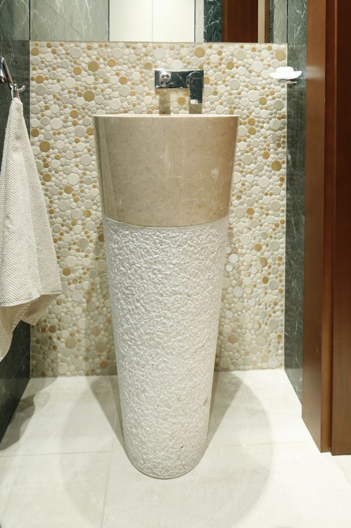 Umywalka podłogowa jest wykonana z beżowego marmuru. Jej oryginalny kształt i fakturę obudowy wyeksponowano na tle okrągłej mozaiki. Fot. Bartosz Jarosz