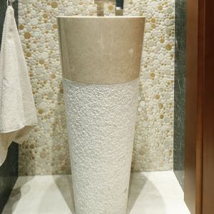 Umywalka podłogowa jest wykonana z beżowego marmuru. Jej oryginalny kształt i fakturę obudowy wyeksponowano na tle okrągłej mozaiki. Fot. Bartosz Jarosz