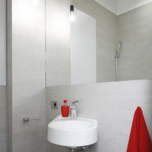 Styl loft w łazience podkreślają minimalistyczne, wiszące lampy w formie żarówek. Optyczne powiększenie zapewnia duże lustro nad małą umywalką. Fot. Bartosz Jarosz