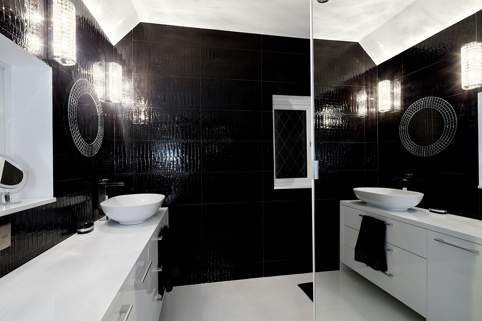 Ogromne lustro na ścianie dwukrotnie powiększa łazienkę. Czarne płytki to stylizacja skóry krokodyla. Fot. Michał Jessa