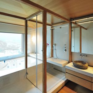 Zabudowa meblowa, drewniane belki oraz sufit wykończony drewnianą deską stwarzają wrażenie naturalnej otuliny, w której zamknięto łazienkę. Projekt: Coblonal Arquitectura. Fot. Coblonal Arquitectura.