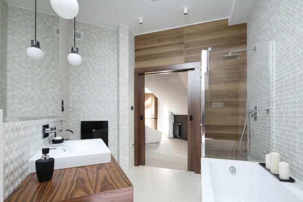 Nowoczesną łazienkę na poddaszu urządzono w bieli i kolorach drewna, a charakteru dodają jej płytki 3D na ścianach.
