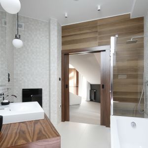 Jasną łazienkę na poddaszu urządzono w nowoczesnym stylu, z dużą ilością bieli ocieplonej kolorami drewna. Projekt: Jan Sikora. Fot. Bartosz Jarosz