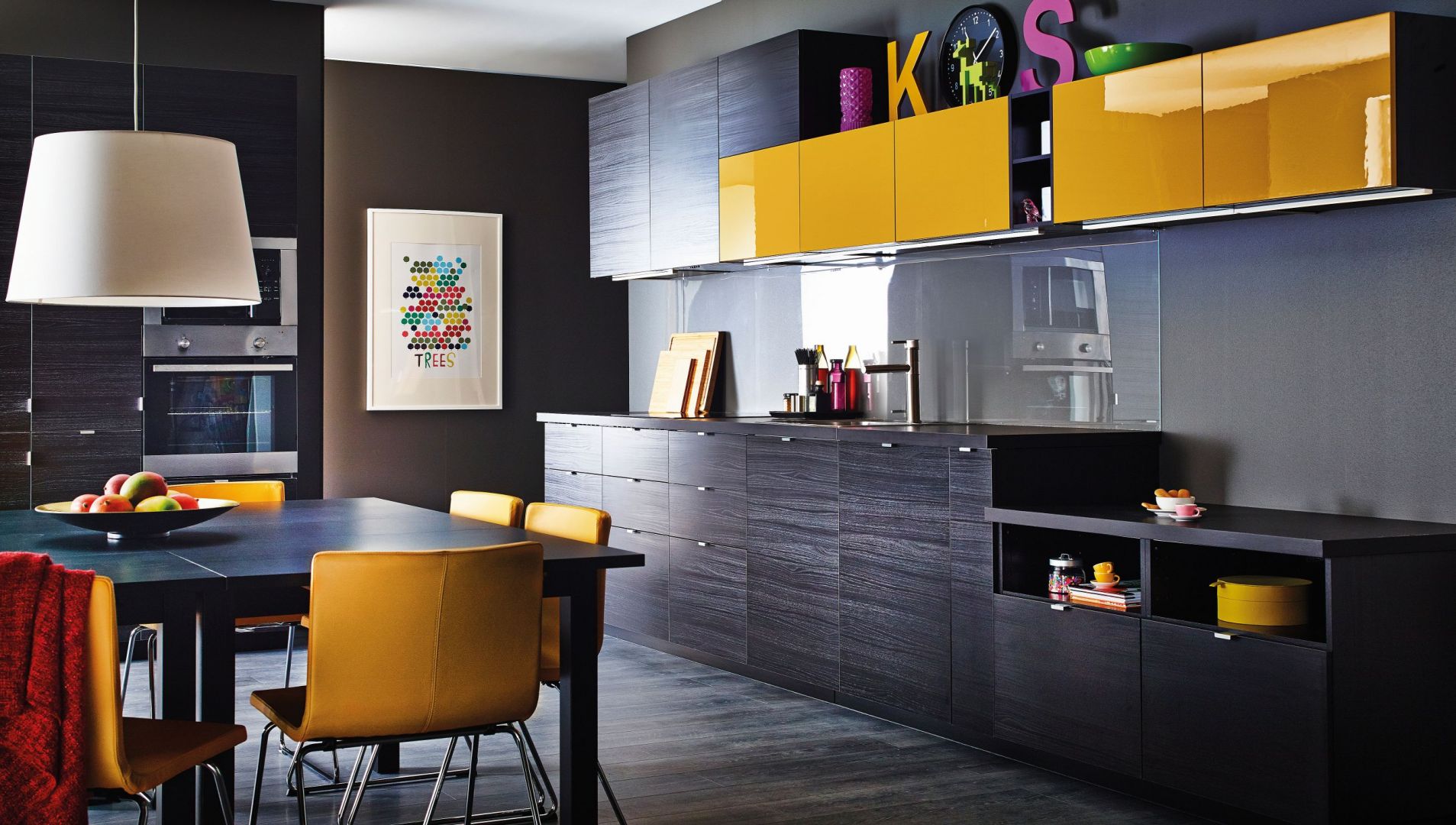 Kuchnia Metod firmy IKEA. Ściana wykończona przezroczystym szkłem
podkreśla ciekawą kolorystykę mebli – imitującą czarne drewno oraz żółty w połysku. Fot.IKEA.