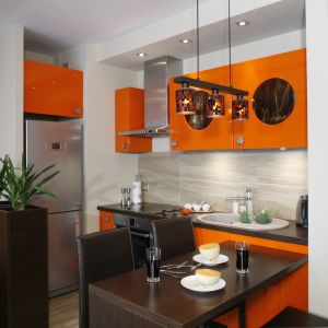 W niedużym aneksie kuchennym dominuje kolor pomarańczowy, którego intensywny odcień łagodzi ciepły brąz. Projekt Jolanta Kwilman. Fot. Bartosz Jarosz.