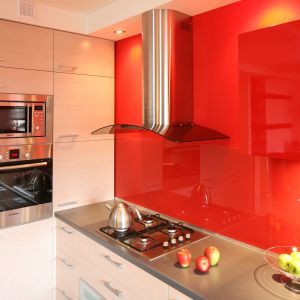 Ściana w kolorze żywej, intensywnej czerwieni jest najbardziej charakterystycznym elementem tej rodzinnej kuchni. Doskonale komponuje się z bielą, jasnym dębem i odcieniami szarości, dodając wnętrzu przytulności i ciepła. Projekt Marta Kruk. Fot. Bartosz Jarosz.
