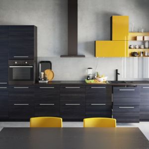 Nowoczesną zabudowę kuchenną wyróżniają żółte fronty lakierowane na wysoki połysk szafek górnych. Kolor szafranu podkreśla ich asymetryczne ułożenie. Fot. IKEA.