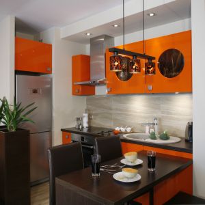 Niewielkich rozmiarów kuchnia urządzona została w soczystym kolorze pomarańczy, który doskonale podkreśla wakacyjny charakter wnętrza. Projekt Jolanta Kwilman. Fot. Bartosz Jarosz.