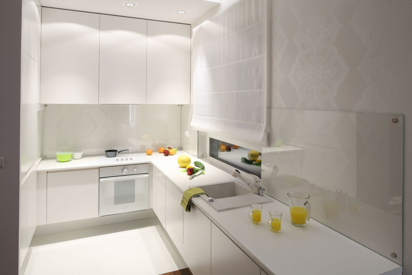 W wąskiej kuchni biel optycznie powiększa przestrzeń, a poprowadzone wzdłuż szafek górnych halogenowe oświetlenie dodatkowo ją rozjaśnia. Projekt Katarzyna Merta-Korzniakow. Fot. Bartosz Jarosz.