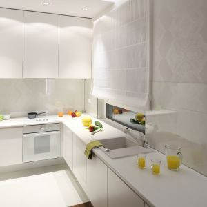 W wąskiej kuchni biel optycznie powiększa przestrzeń, a poprowadzone wzdłuż szafek górnych halogenowe oświetlenie dodatkowo ją rozjaśnia. Projekt Katarzyna Merta-Korzniakow. Fot. Bartosz Jarosz.