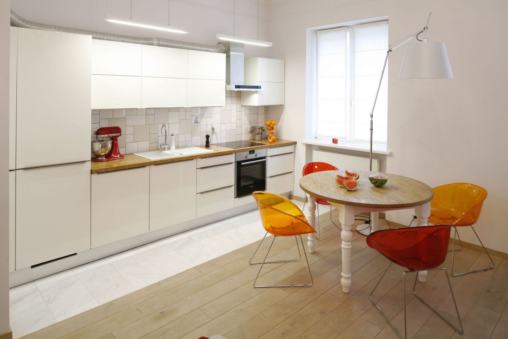 W otwartej na salon kuchni zdecydowano się na zabudowę kuchenną na jedną ścianę.  Szafki górne w białym kolorze nie tylko zapewniają sporo miejsca do przechowywania, ale też optycznie powiększają przestrzeń. Projekt: Agnieszka Żyła. Fot. Bartosz Jarosz.