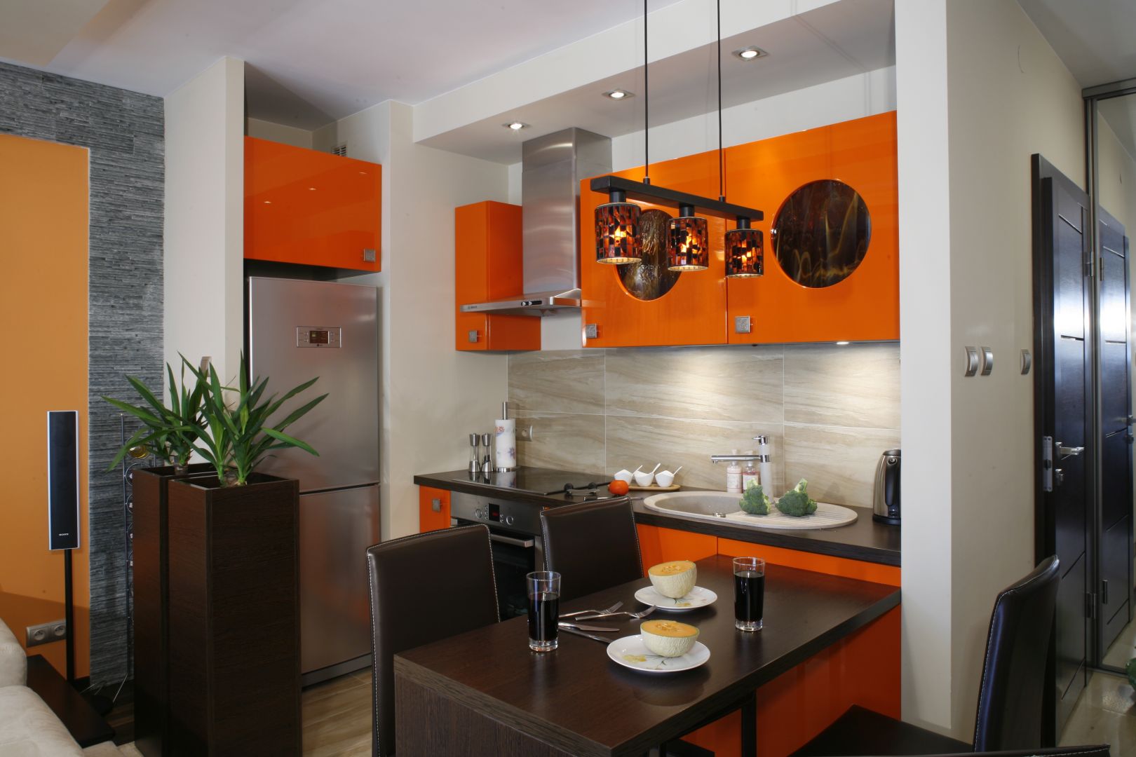 Niewielkich rozmiarów kuchnia urządzona została w soczystym kolorze pomarańczy, który doskonale podkreśla wakacyjny charakter wnętrza. Projekt Jolanta Kwilman. Fot. Bartosz Jarosz.