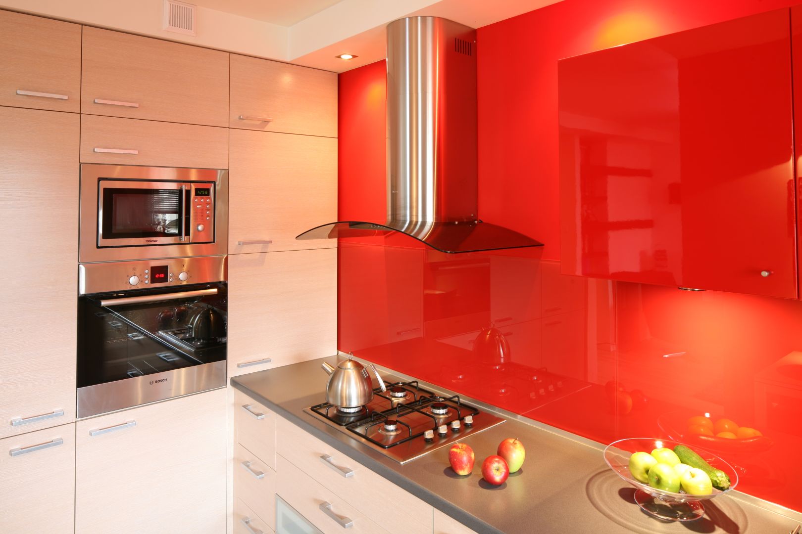 Energetyzująca czerwień zdominowała jedną ze ścian w kuchni. Wykonana z lakierowanego na wysoki połysk MDFu szafeczka właściwie wtapia się w przestrzeń. Projekt Marta Kruk. Fot. Bartosz Jarosz.