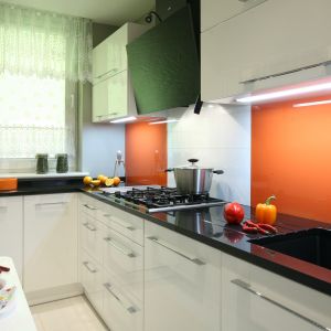 Ścianę nad blatem wykończono (tylko częściowo) lakierowanym szkłem w kolorze pomarańczowym, które ociepla wnętrze. Projekt: Zbigniew Bąba, Arkadiusz Jelito. Fot. Bartosz Jarosz. 