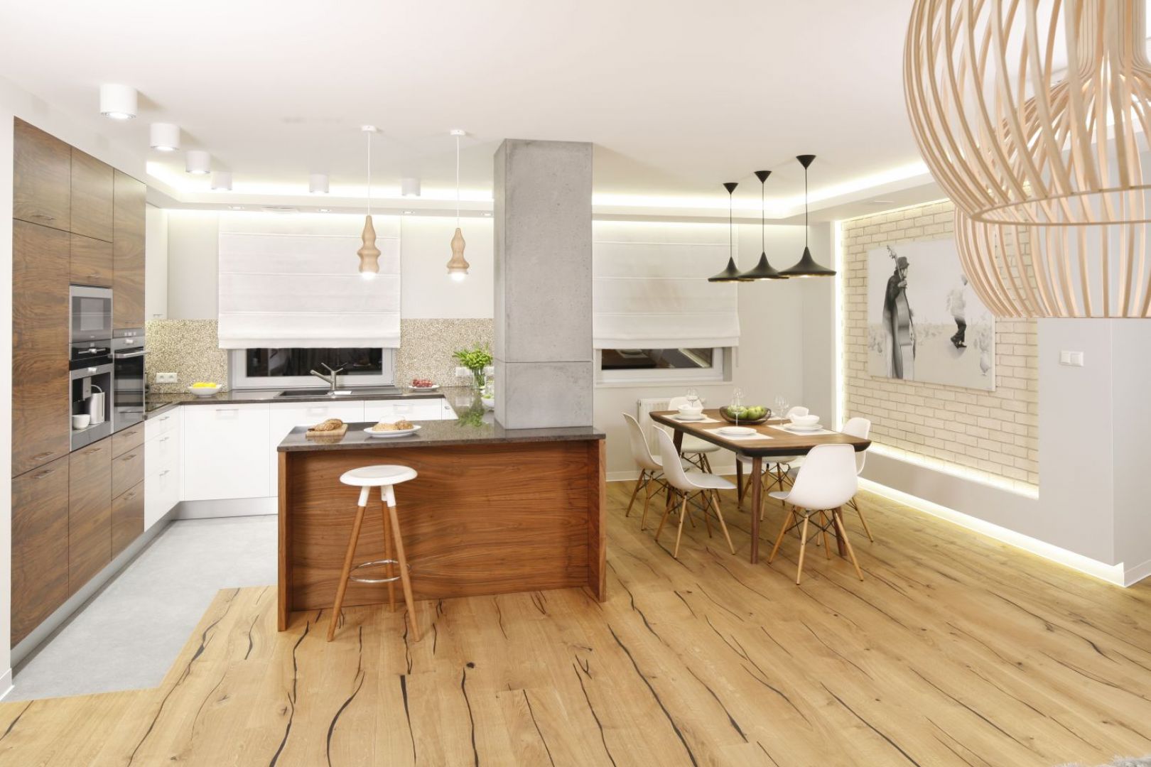 Kuchnia płynnie łączy się z salonem i jadalnią. Stylistycznie wszystkie przestrzenie spajają użyte w aranżacji materiały, w tym beton. Projekt Agnieszka Hajdas-Obajtek. Fot. Bartosz Jarosz.