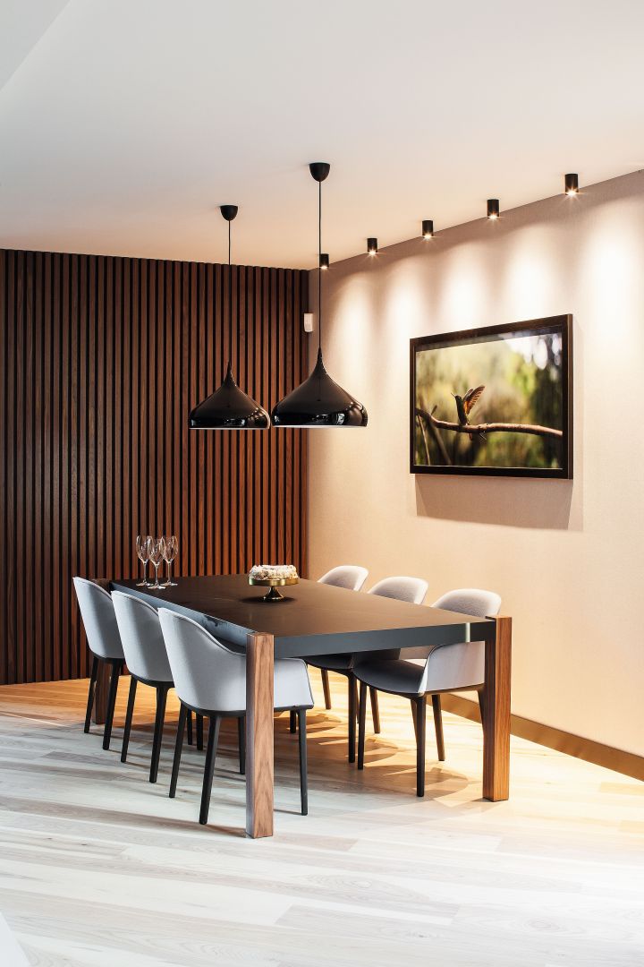 Jadalnia zachwyca stylem i elegancją. Jest formalna i rodzinna zarazem. Dobry design połączono z funkcjonalnością kompletując kultowe krzesła Softshell marki Vitra z drewnianym stołem.