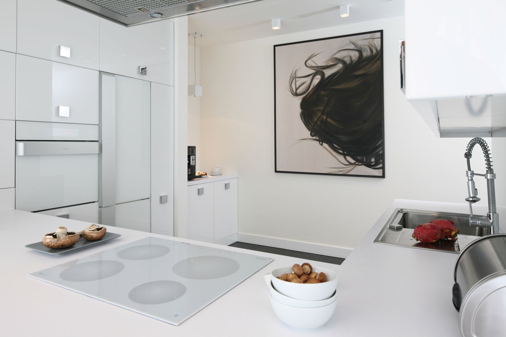 W przestronnej kuchni biel w wysokim połysku podkreśla salonowy charakter aranżacji przestrzeni. Projekt Dominik Respondek. Fot. Bartosz Jarosz.