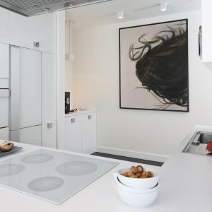 W przestronnej kuchni biel w wysokim połysku podkreśla salonowy charakter aranżacji przestrzeni. Projekt Dominik Respondek. Fot. Bartosz Jarosz.