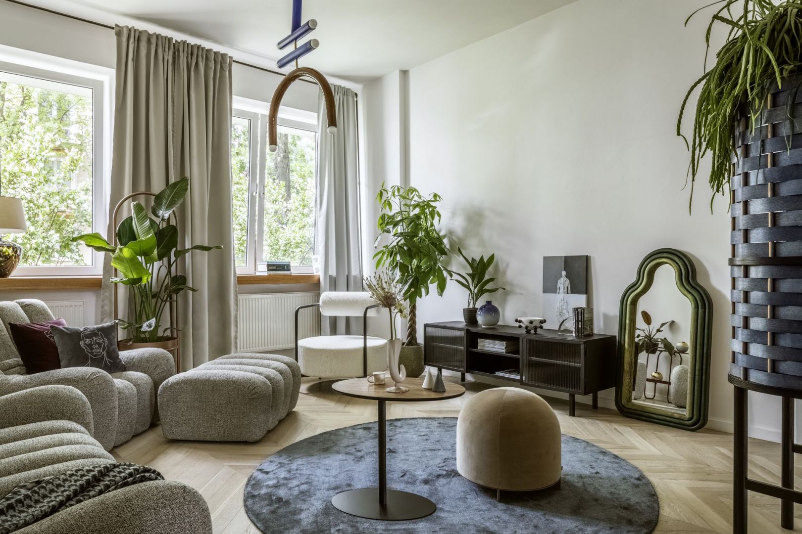 Kanapa, fotel oraz podnóżek Wadi projektu Tomka Rygalika; stolik Nato (Nobonobo), lampa Parma (4Concepts), kwietnik Hula (Bujnie), fotel Saffron (The Good Living & Co), rośliny (Plants For Humans), komoda rtv Object023 (NG Design), lustro TRN mirror / triple ; lampa TRN Light F2 (Pani Jurek), solniczka i pieprzniczka Cone (Tre Product), pufa Stado (Nurt), wazon Irena (Malwina Konopacka), dywan (Carpet Decor), obraz Touch & Movement (AINA), regał projektu Beza Projekt x SSF (Splot).