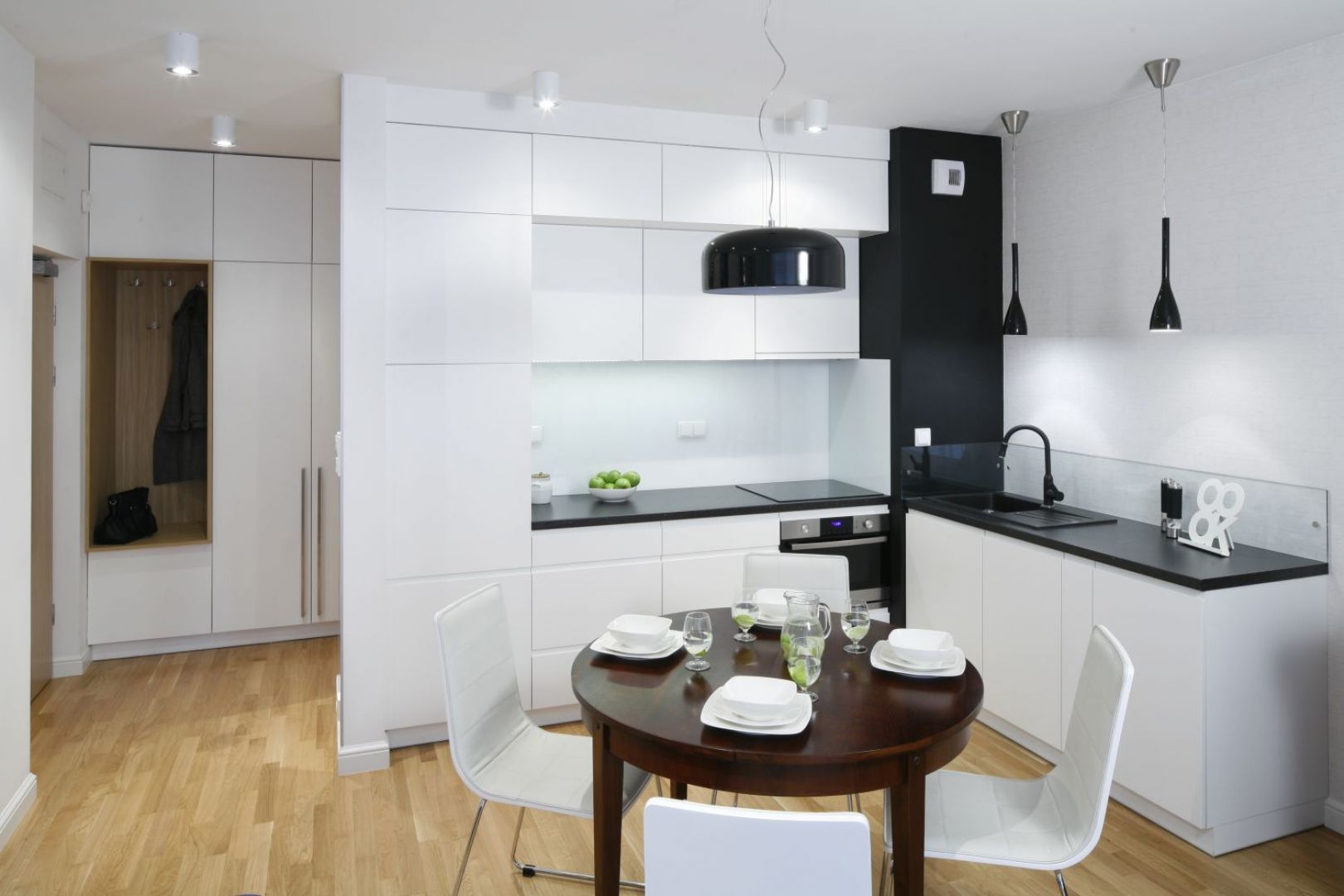 Przy niedużym aneksie kuchennym zaplanowano równie niedużą jadalnię. Kontrast bieli i czerni prezentuje się bardzo elegancko. Projekt: Ewa Para. Fot. Bartosz Jarosz