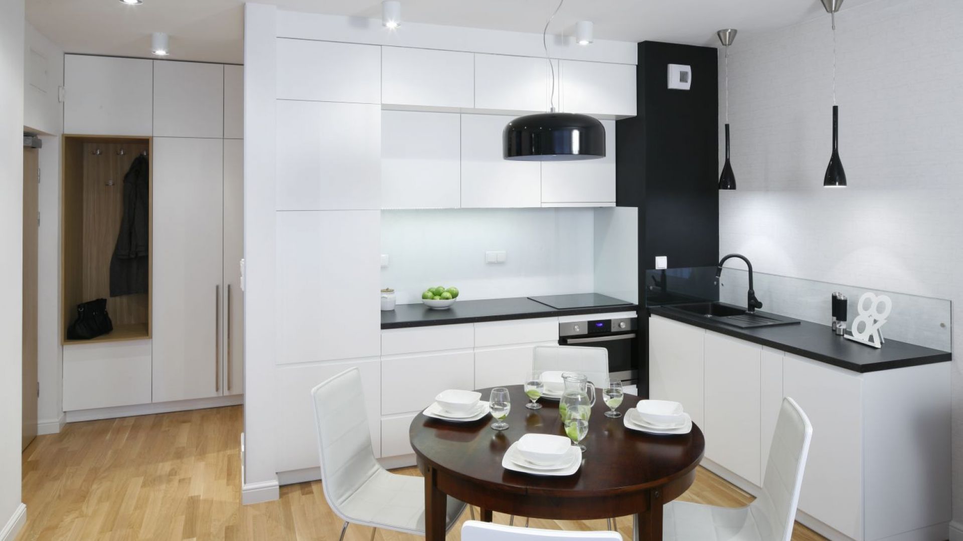 Przy niedużym aneksie kuchennym zaplanowano równie niedużą jadalnię. Kontrast bieli i czerni prezentuje się bardzo elegancko. Projekt: Ewa Para. Fot. Bartosz Jarosz