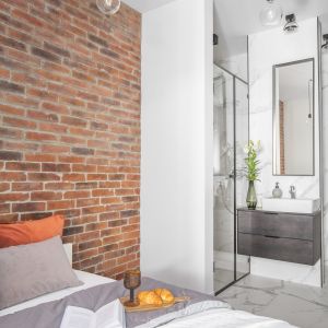 Do wykończenia ścian za kanapą w salonie oraz za łóżkiem w sypialni architekci zastosowali okładzinę  z cegły Milke, która nadała mieszkaniu industrialny klimat. 
