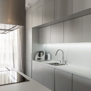 Proste formy mebli, sięgające od podłogi aż do sufitu, architekt Patrycja Dmowska połączyła z chłodem kamiennego blatu i chromowaną armaturą. Projekt: Patrycja Dmowska, biuro projektowe Dmowska Design. Zdjęcia: Przemysław Kuciński