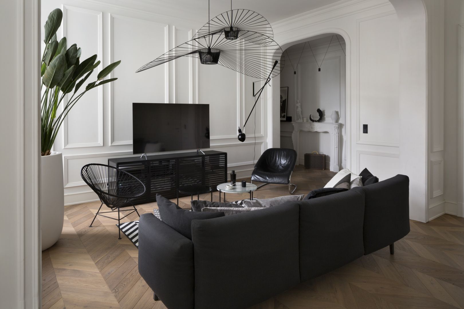 Drewniana podłoga ułożona w jodłę francuską prowadzi nas do salonu z kuchnią. Projekt Goszczdesign. Fot. Piotr Mastalerz