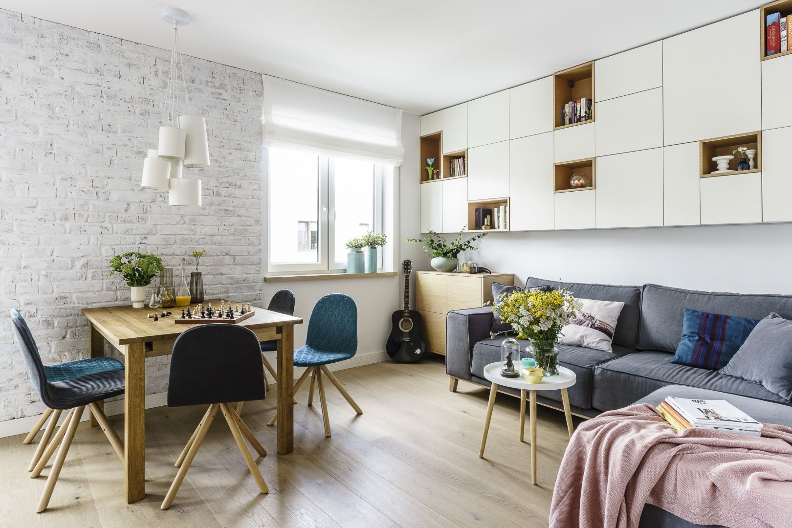 Salon z jadalnią, ulokowaną zazwyczaj w pobliżu otwartej kuchni, sprawdzi się zarówno w obszernych, jak i niedużych mieszkaniach. Projekt Saje Architekci. Fot. Fotomohito