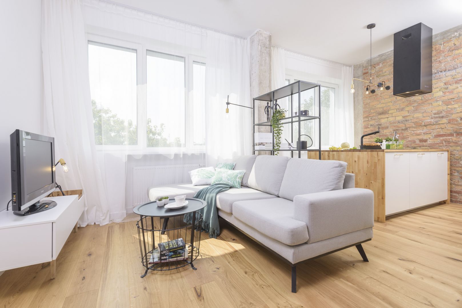 Salon, będący częścią otwartej strefy dziennej, urządzono w jasnych kolorach. Aranżacji pazura dodaje jedna ściana wykończona cegłą. Projekt i zdjęcia: Katarzyna Kiełek, Agnieszka Komorowska-Różycka