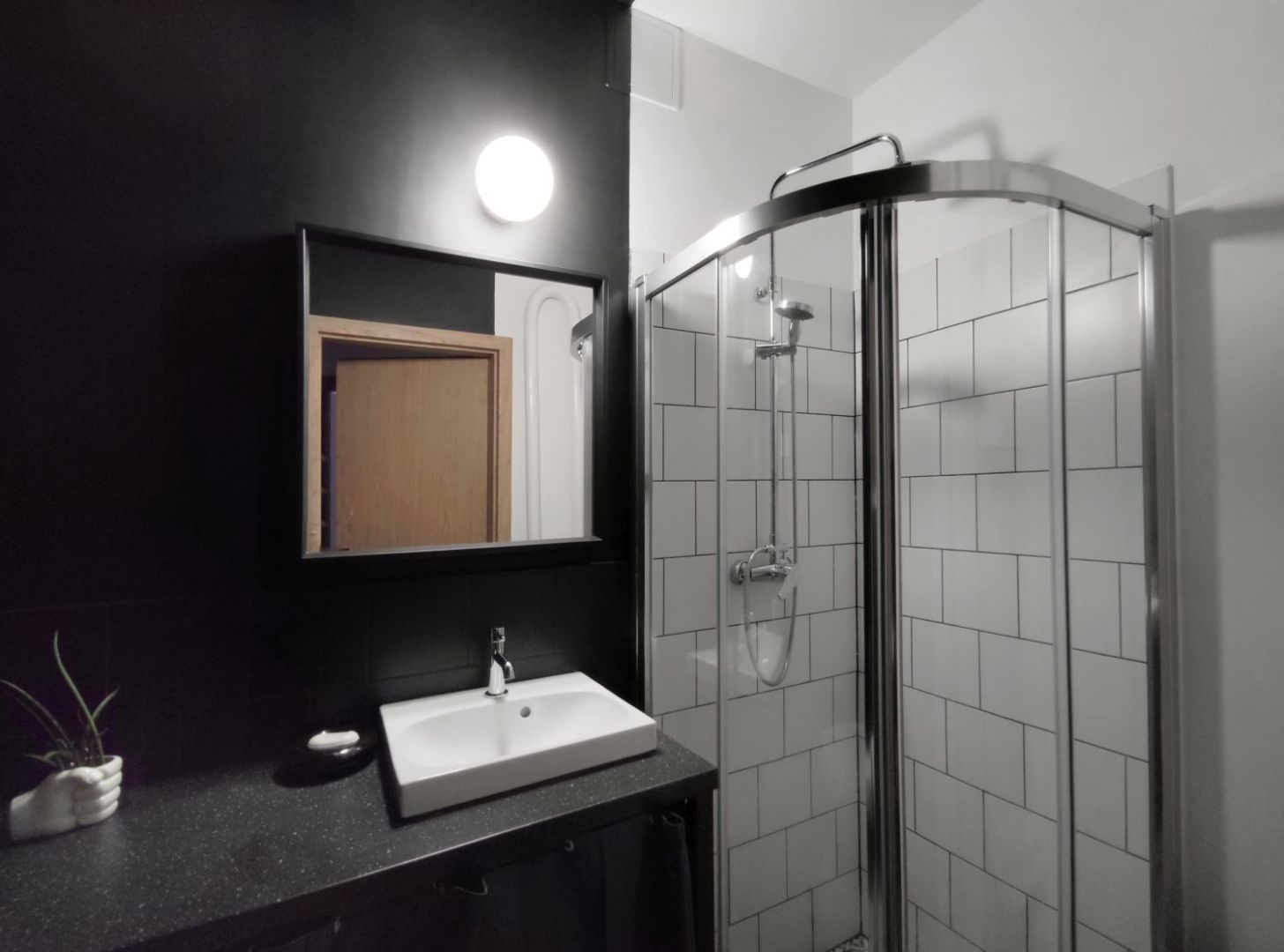Niewielką łazienkę podzielono na strefę czarną, w której znalazła się toaleta i umywalka oraz białą – z kabiną prysznicową. Projekt: Agnieszka Musiał. Fot. Musiał Studio