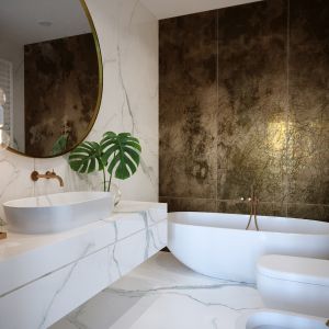 W tej łazience głównym elementem dekoracyjnym jest ściana z płytek w kolorze starego złota. Projekt JMW Architekci