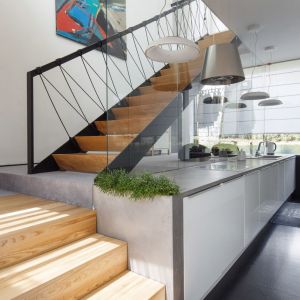 Ciekawe nowoczesne schody z drewnianymi stopniami i balustrada ze szkła i metalu. Projekt arch. Robert Skitek, pracownia RS+. Zdjęcia Tomasz Zakrzewski