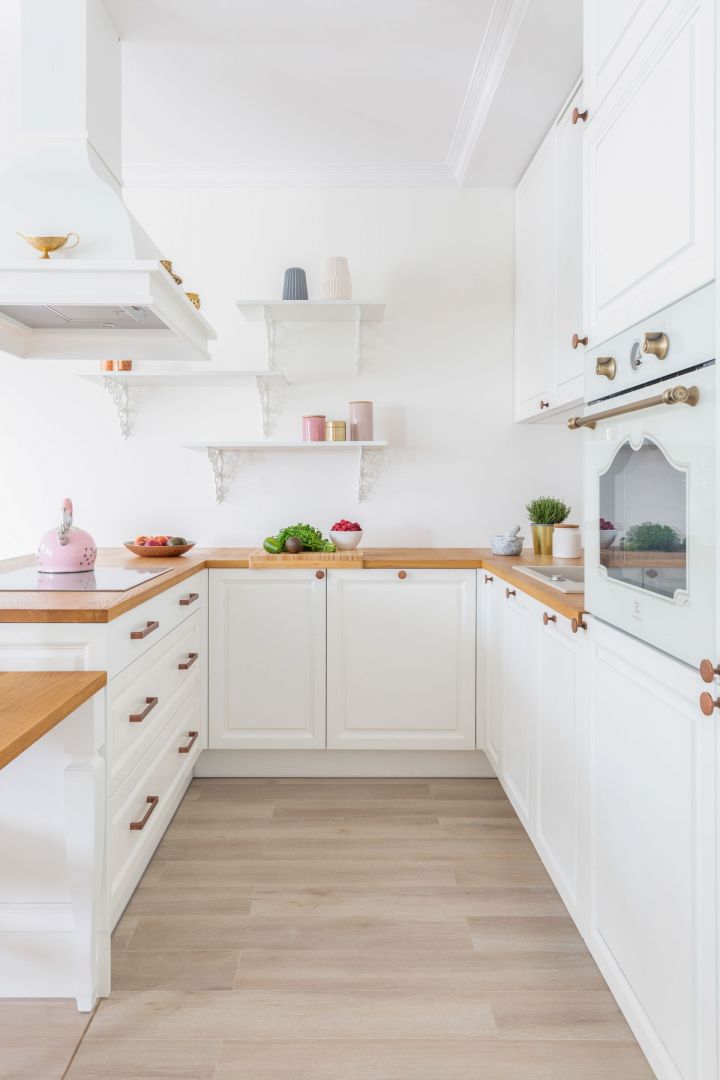 Kuchenne meble wykonano z drewna. Bielone ramkowe fronty zdobione frezem połączono z blatami z litego dębowego drewna. Projekt wnętrza: Architekt wnętrz Ewa Masztakowska, Decoroom. Projekt kuchni i zabudowy meblowej: Architekt wnętrz Katarzyna Fotek, Decoroom. Zdjęcia i stylizacja: Marta Behling, Pion Poziom – fotografia wnętrz