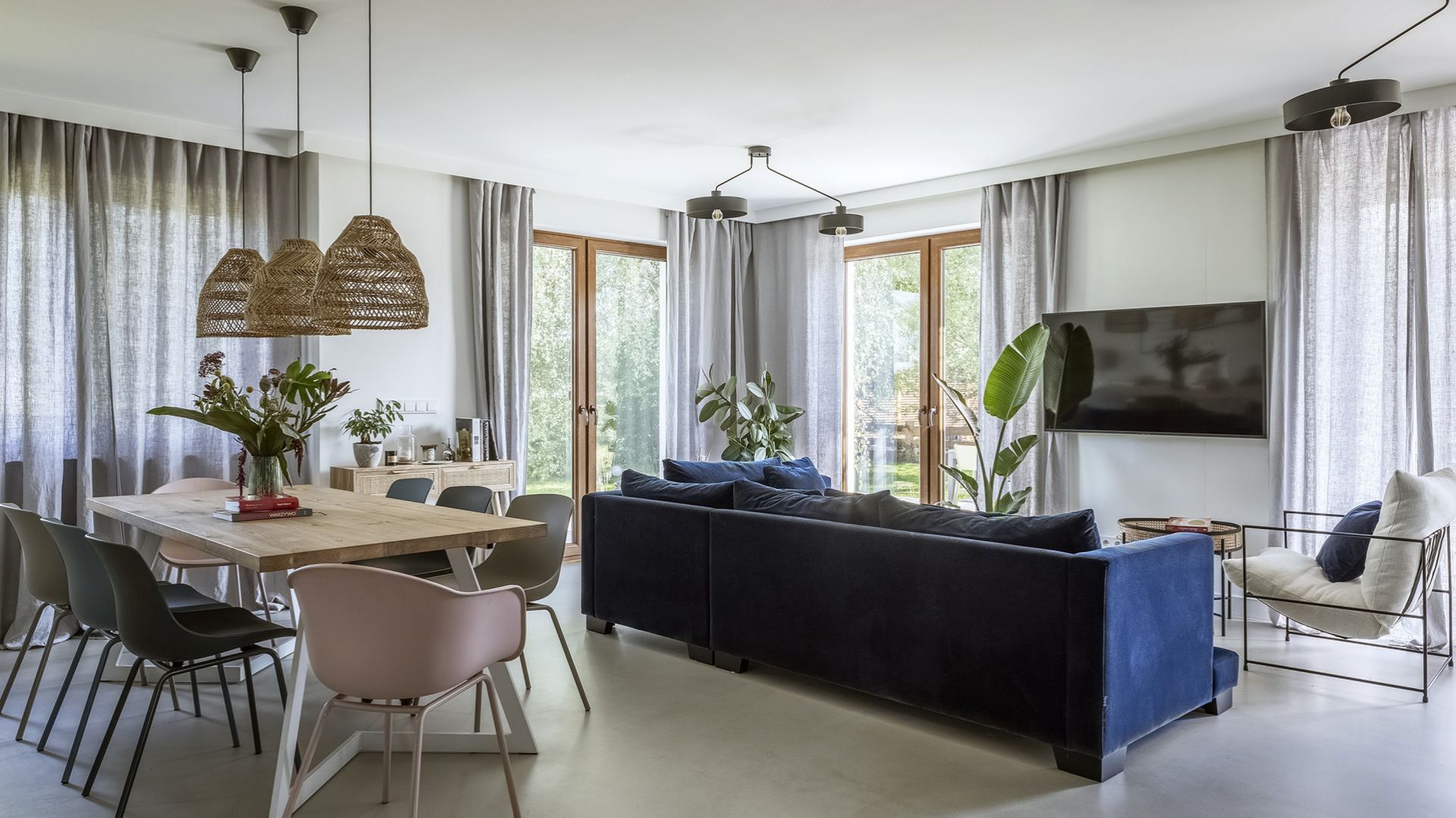 W tym salonie szare przejrzyste zasłony z ukrytym karniszem ocieplają wnętrze i dodają mu elegancji. Projekt Malwina Morelewska. Fot. Yassen Hristov