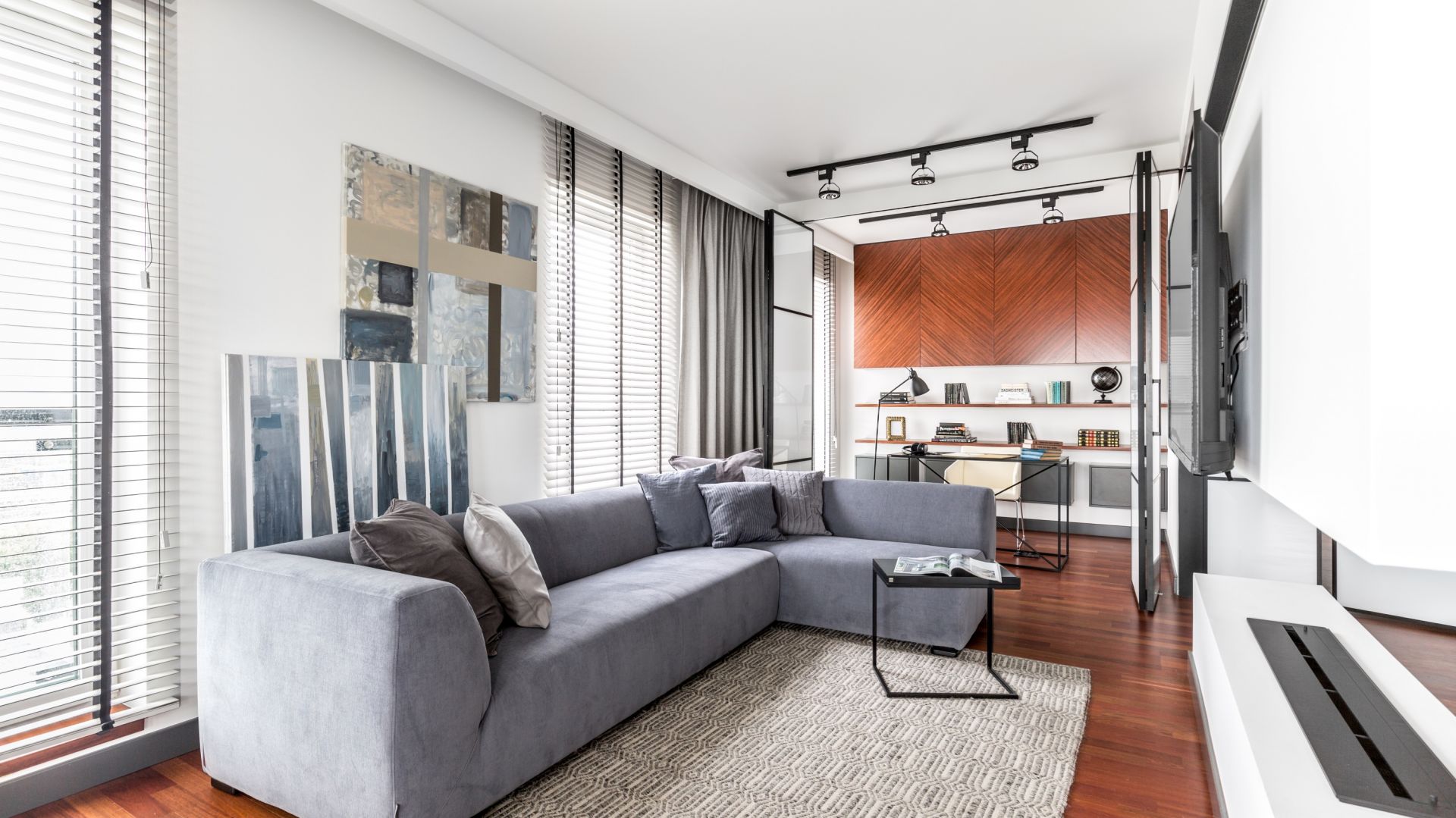 Szary narożnik o efektownej formie podkreśla nowoczesny charakter salonu. Projekt Decoroom