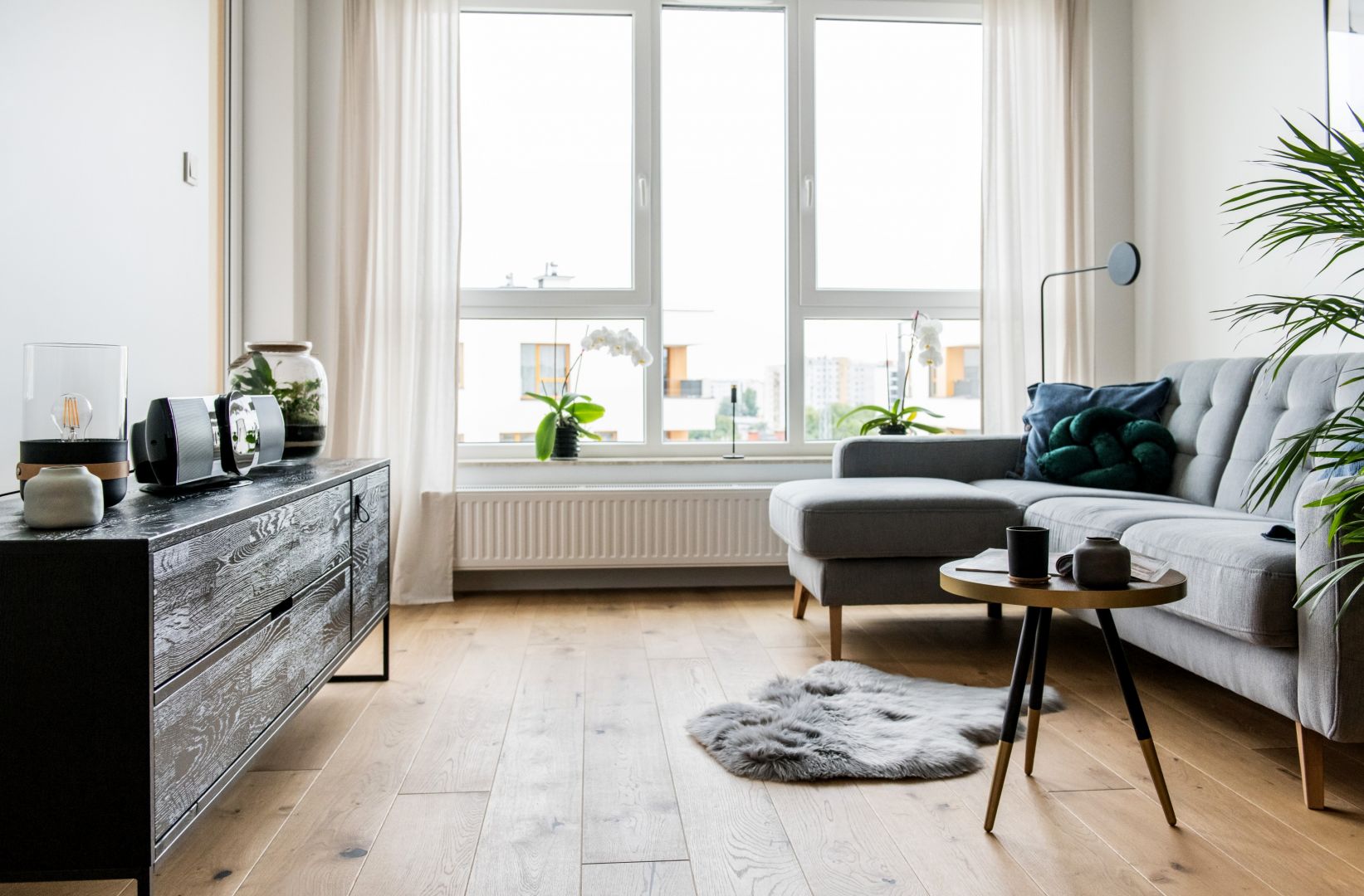 Przez duże okna wpada światło dzienne, które rozświetla salon. Projekt i zdjęcia Deer Design