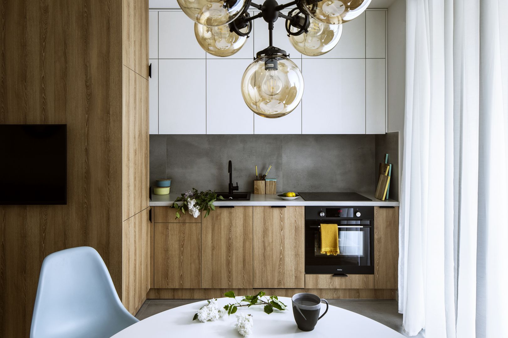 Białe szafki górne powiększają małą kuchnię. Projekt Poco Design.Foto Yassen Hristov