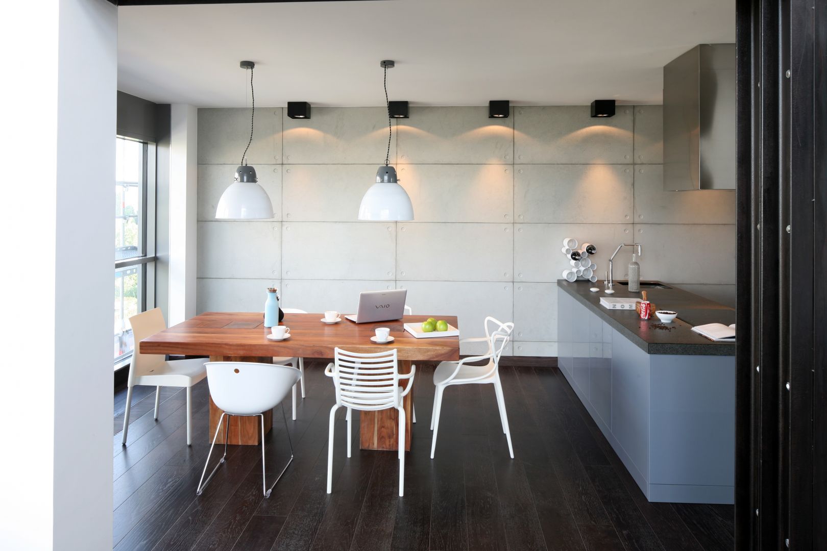 Beton na ścianie, masywny, drewniany stół i białe, lekkie krzesła to świetny wybór do jadalni w stylu loft. Projekt: Justyna Smolec. Fot. Bartosz Jarosz