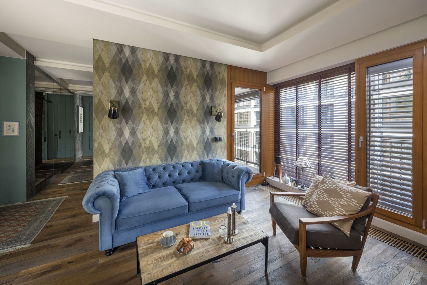 Błękitna, welurowa sofa w salonie pięknie prezentuje się w połączeniu z fotelem w stylu industrialnym. Projekt: Magdalena Miśkiewicz. Fot. Łukasz Zandecki