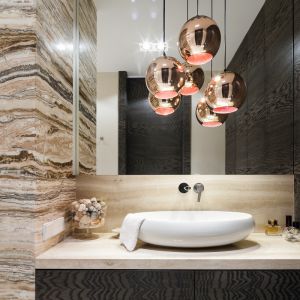 Стена в ванной отделана натуральным камнем травертином над раковиной и красивым ониксом.  Дизайн Агнешки Людвиновской.  Фото  Бартош Ярош